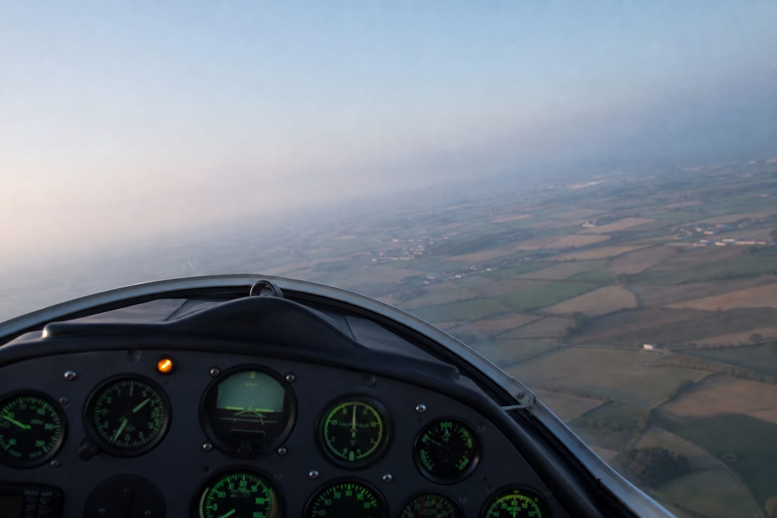 Right seat view in flight with a high nose attitude, green backlit gauges and a lit amber warning lamp